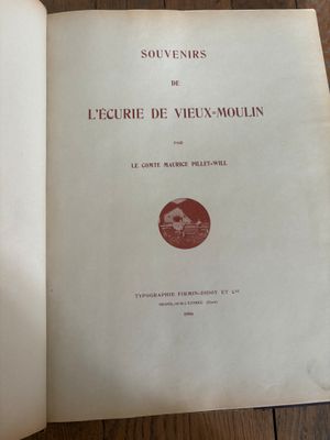 un livre ouvert posé sur un parquet, à côté d'une table en bois