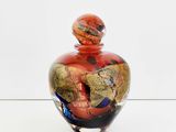 a glass vase with a red and black design on it