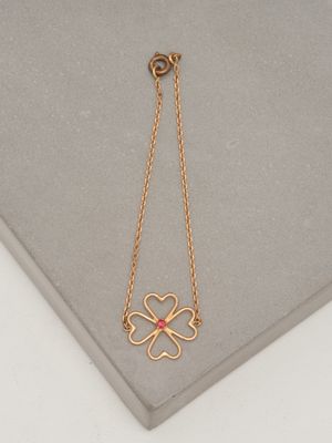 a close up of a gold necklace with a four leaf clover on it