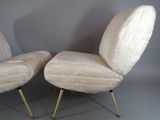 two white chairs with gold legs and a white wall behind them