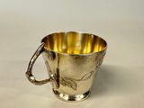 an antique silver cup with a handle on a white surface