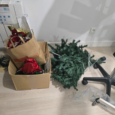 a christmas tree in a box on the floor next to an office chair