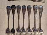 six fourchettes et une cuillère sont disposées en rang sur une table