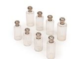 six clear glass bottles with silver lids and a silver top