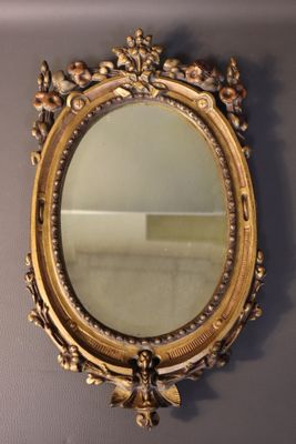 an ornate gold framed mirror on a wall in a room