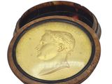 a gold coin in a wooden box with a picture of a man on it