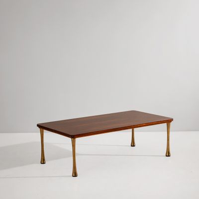 une table basse avec des pieds en laiton et un plateau en bois