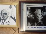 Deux photos encadrées représentant des hommes sont posées sur un plancher en bois, à côté d'un portrait d'un homme