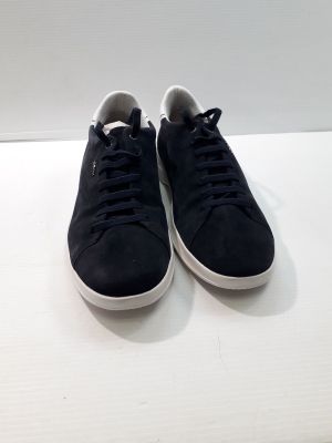 baskets en daim noir à semelles blanches posées sur une surface blanche