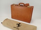 brown leather briefcase with a horse logo on it next to a brown case