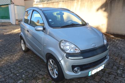 a small silver car parked on a cobblestone street
