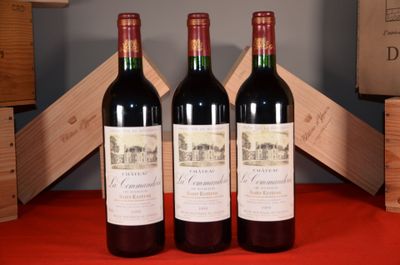 three bottles of red wine sit on a table next to a wooden crate