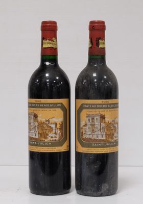two bottles of wine sitting next to each other on a white surface