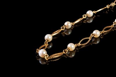 collier de perles et d'or sur fond noir