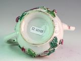 a white cup with a green and pink decoration on it