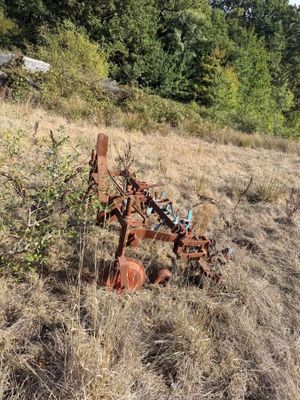 a rusted plow sitting in the middle of a field