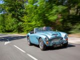 a blue car driving down the road with trees in the background