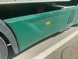 a green semi truck with a flat bed parked in a parking lot