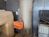 un grand réservoir métallique posé à côté d'une pile de bois