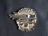 a silver brooch with a bird on top of it
