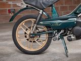a green motorcycle that is parked in front of a brick wall