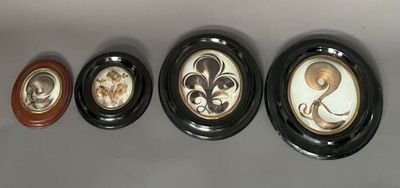 four oval picture frames mounted on a wall with a fleur de lis design