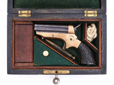 une boîte en bois contenant un pistolet et une balle