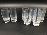 six verres à shot transparents alignés sur une surface noire