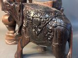 a small elephant statue next to a vase on a table