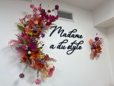 a wall with flowers and a sign that says madame au style