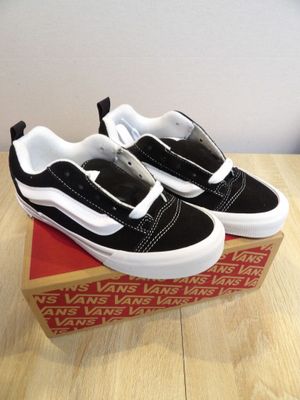 black and white vans slip ons on a box on a wooden table