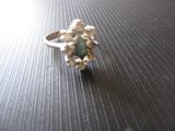 une bague en argent sertie d'une pierre verte, posée sur une table