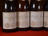 four bottles of wine are lined up on a red table
