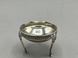 un plat ancien en argent posé sur un socle, sur une surface grise