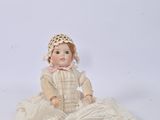 a doll that is sitting on the ground with a hat on