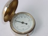 a small brass clock with a white dial on it