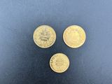 trois pièces d'or posées sur une surface noire