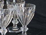 four clear glass goblets sitting on top of a black table