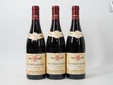 three bottles of red wine are lined up on a white surface