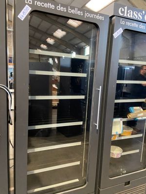 two refrigerators that have food inside of them in a store