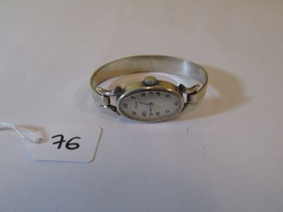 une montre-bracelet en argent posée sur une table blanche, avec une étiquette de prix