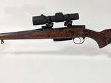 le fusil est posé sur un support transparent équipé d'une lunette de visée