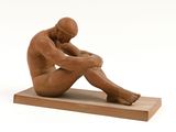 statue d'un homme assis sur un socle en bois, les mains posées sur les genoux