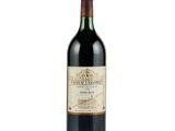 the bottle of red wine is sitting on a white surface