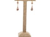 a pair of red and gold earrings on a stand