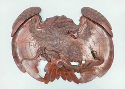 une sculpture en bois représentant un aigle sur lequel est posé un serpent