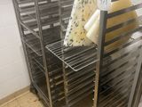 Plusieurs plateaux de fromage sont posés sur une grille métallique dans une cuisine