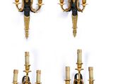 four gold and black wall sconces with candles on each of them