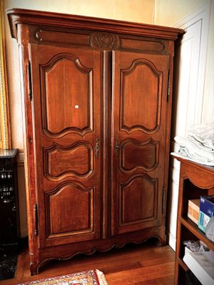a wooden armoire in a room with a rug on the floor