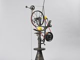 a sculpture of a spinning machine with yellow balls on top of it